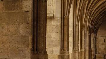 A stone corridor with pointed arches and columns, typical of Gothic architecture.