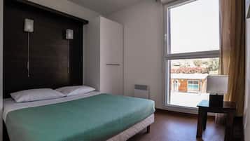A bedroom with a bed, a window, and a nightstand.