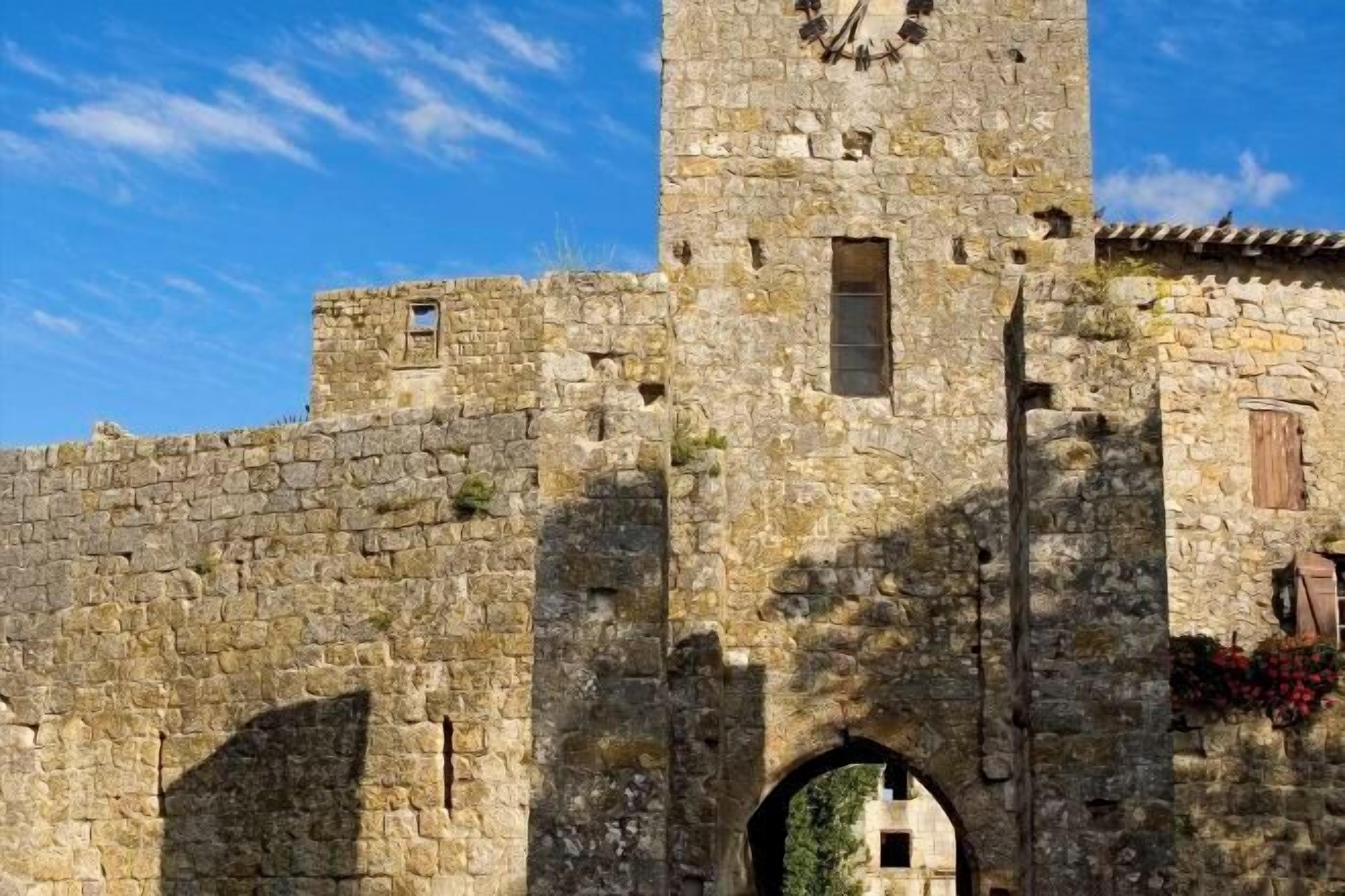 Une tour en pierre, dotée d’une horloge, d’ouvertures en arc de cercle et d’une apparence rustique.