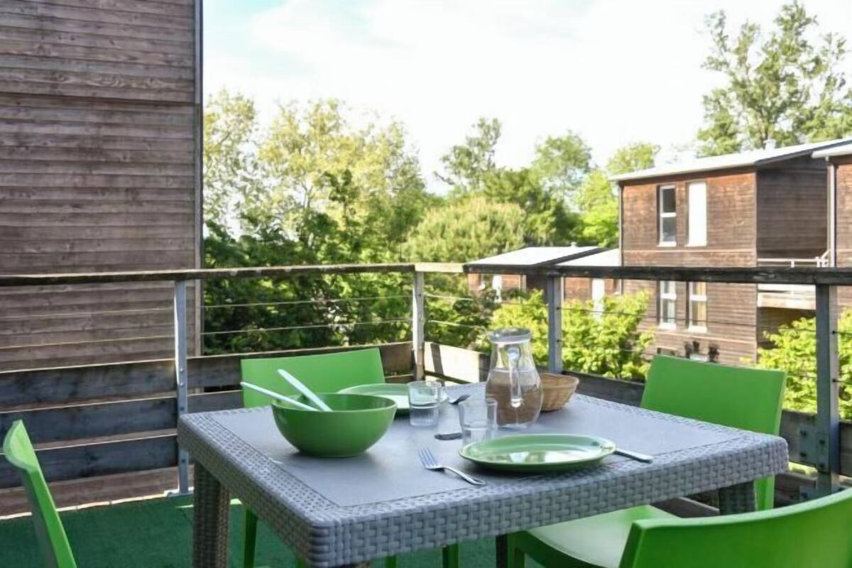 Een balkon buiten met een eettafel, omringd door groene stoelen.