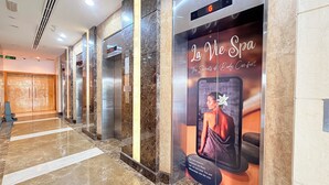Vestíbulo de hotel con suelo de mármol, ascensores y un anuncio de spa.