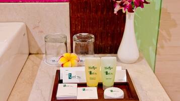 A tray with hotel amenities including shampoo, conditioner, bath foam, and a toothbrush.