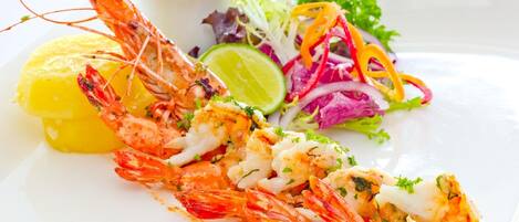 A plate with grilled shrimp, a lime wedge, and a colorful salad.