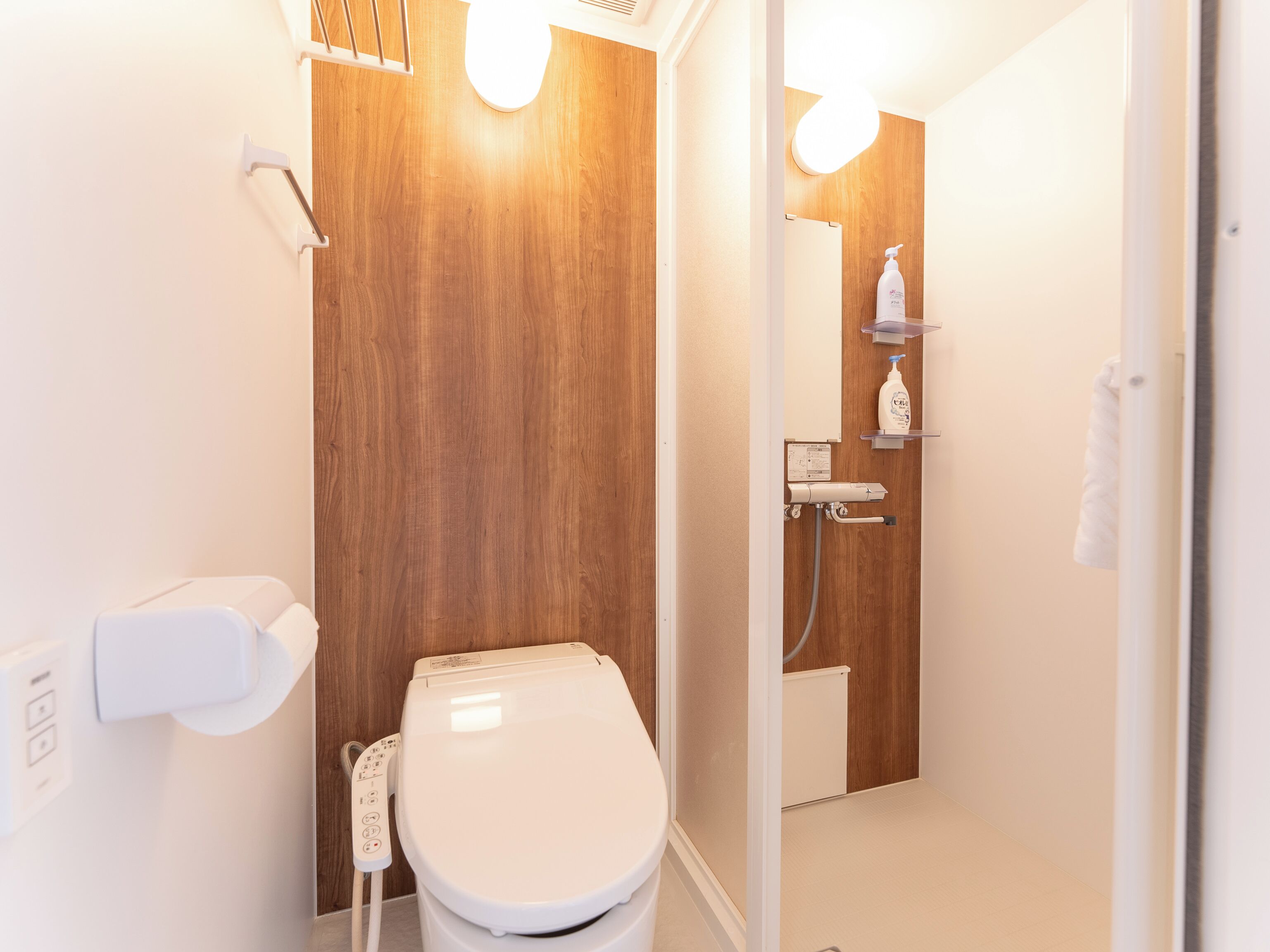A modern bathroom with a wooden vanity, a toilet, and a shower area.