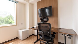 Un espace de bureau moderne comprenant un bureau, une chaise et un téléviseur fixé au mur.