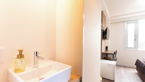 Une salle de bain moderne avec un lavabo blanc, un flacon de savon et un miroir.