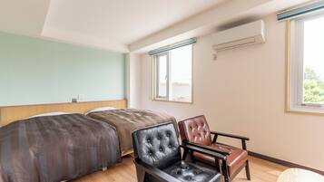 A bedroom with two beds, a chair, a window, and an air conditioning unit.
