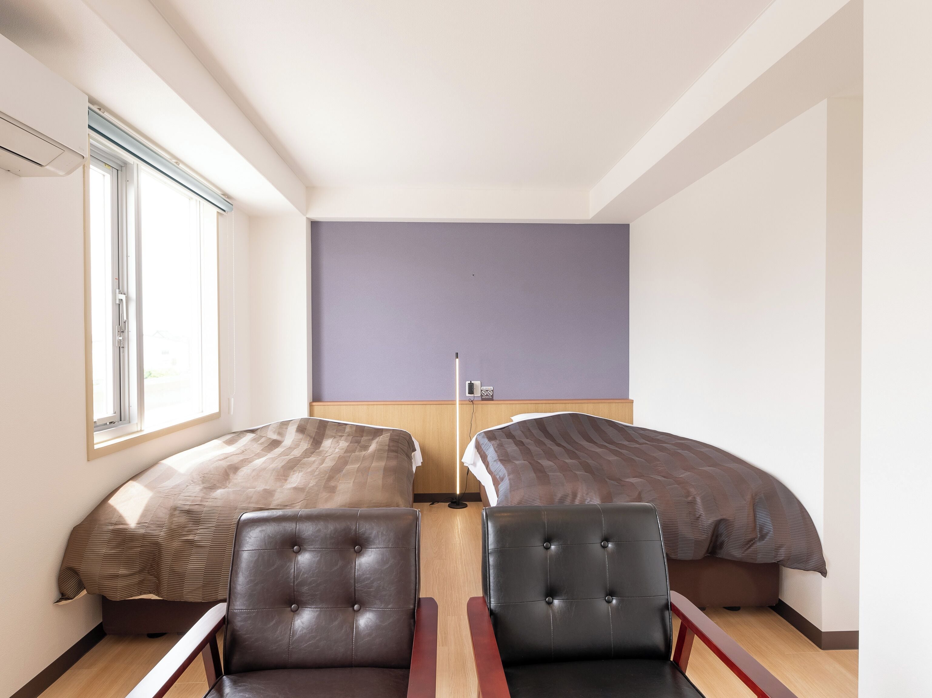 Una habitación con dos camas, una silla y una mesita de noche.