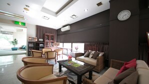 A spacious lobby with a reception desk, seating area with chairs and sofas, a clock on the wall, and a large window with curtains. - Mito Hotel Season (Mito)