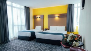 A hotel room with two beds, a small table with a vase of flowers, and a chair.