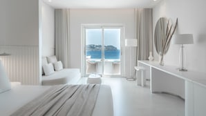 Ett modernt hotellrum med en stor säng, en sittgrupp med utsikt över havet och en balkong.