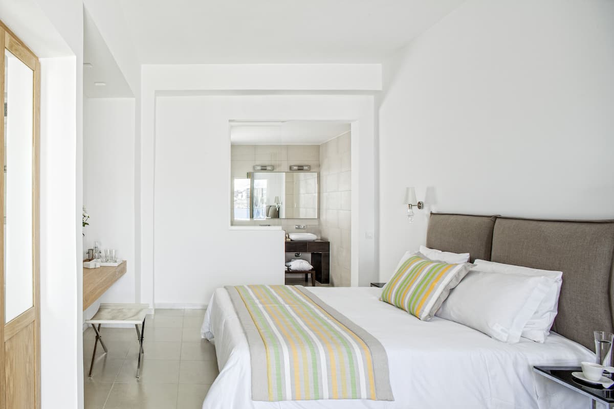 A hotel room with a bed, bedside table, and a bathroom visible through an open door.