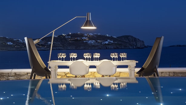 En infinitypool med ett bord för två, omgiven av stolar, och en lampa ovanför.