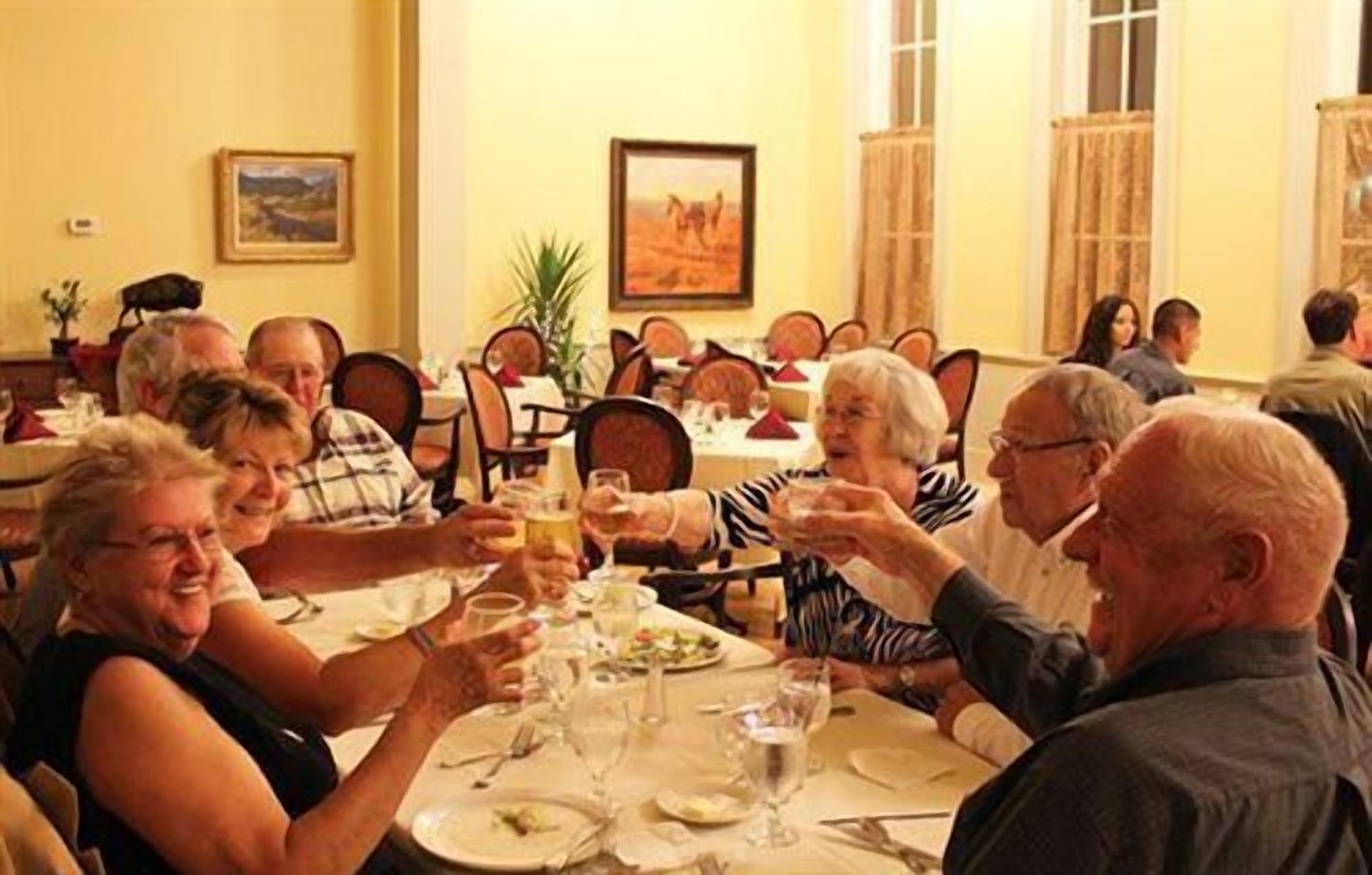 Un grupo de personas sentadas en una mesa en un comedor, con sillas y mesas dispuestas en fila.