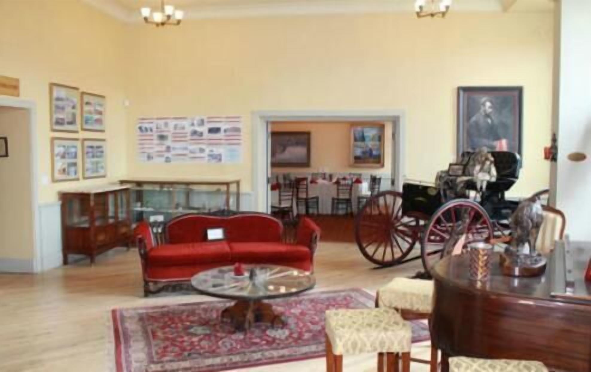 A spacious living room with a red sofa, a glass coffee table, and a dining area with a wooden table and chairs.