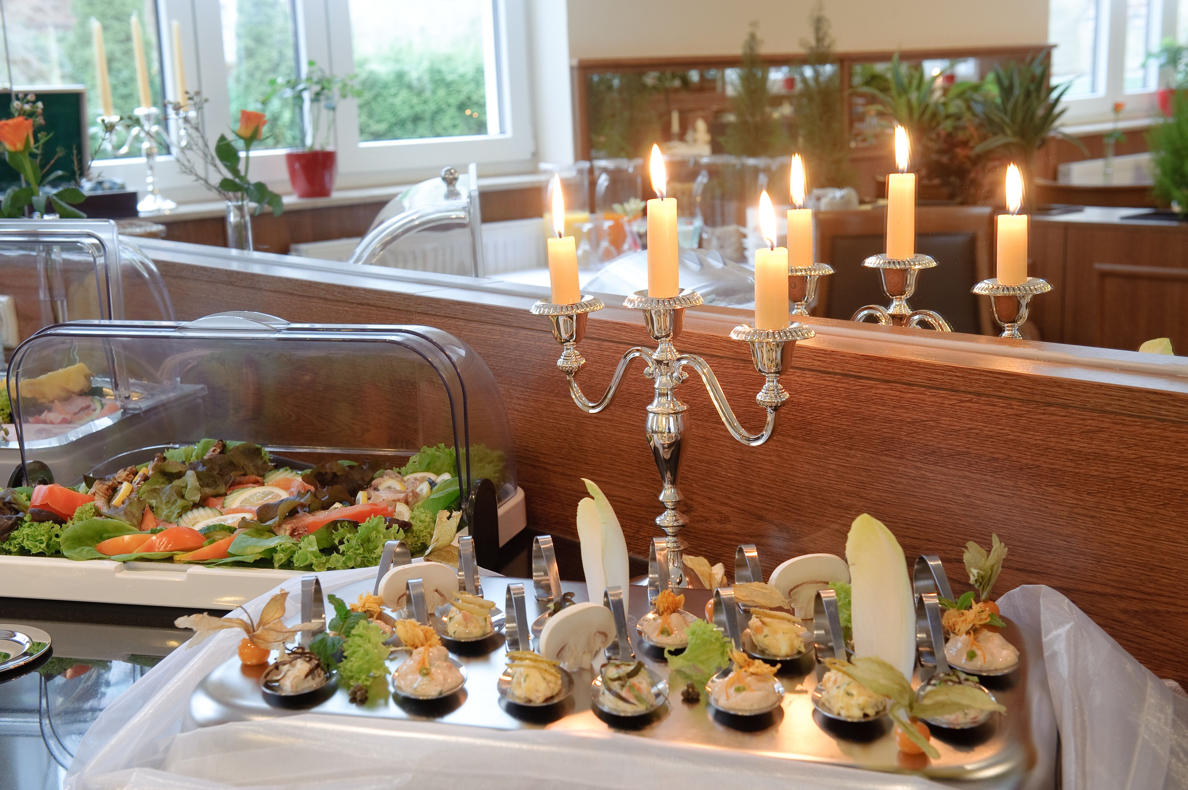 Montaje de bufé con diversas opciones de comida y un candelabro con velas encendidas.