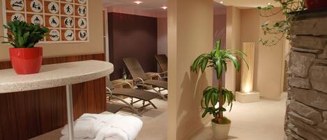 A spa area with a reception desk, lounge chairs, and a wall with service icons.