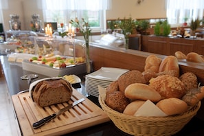 Een buffetopstelling met verschillende broden, een snijplank en een mes.