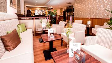 A hotel lobby with striped sofas, wooden tables, and potted plants.