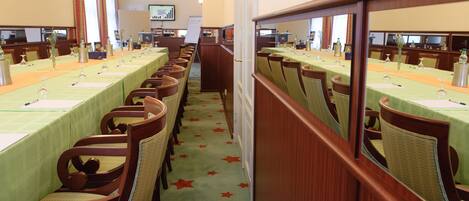 Une salle de conférence avec de longues tables, des chaises et un tapis orné d’étoiles rouges.