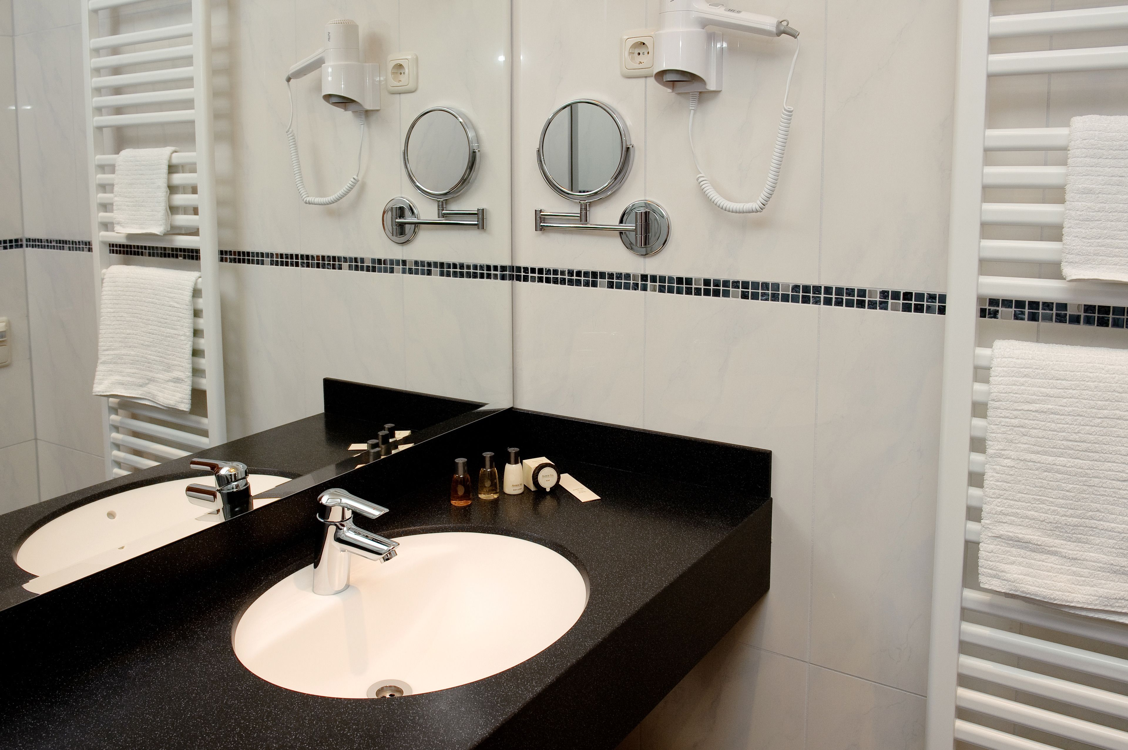 A bathroom with two sinks, a mirror, and a towel rack.