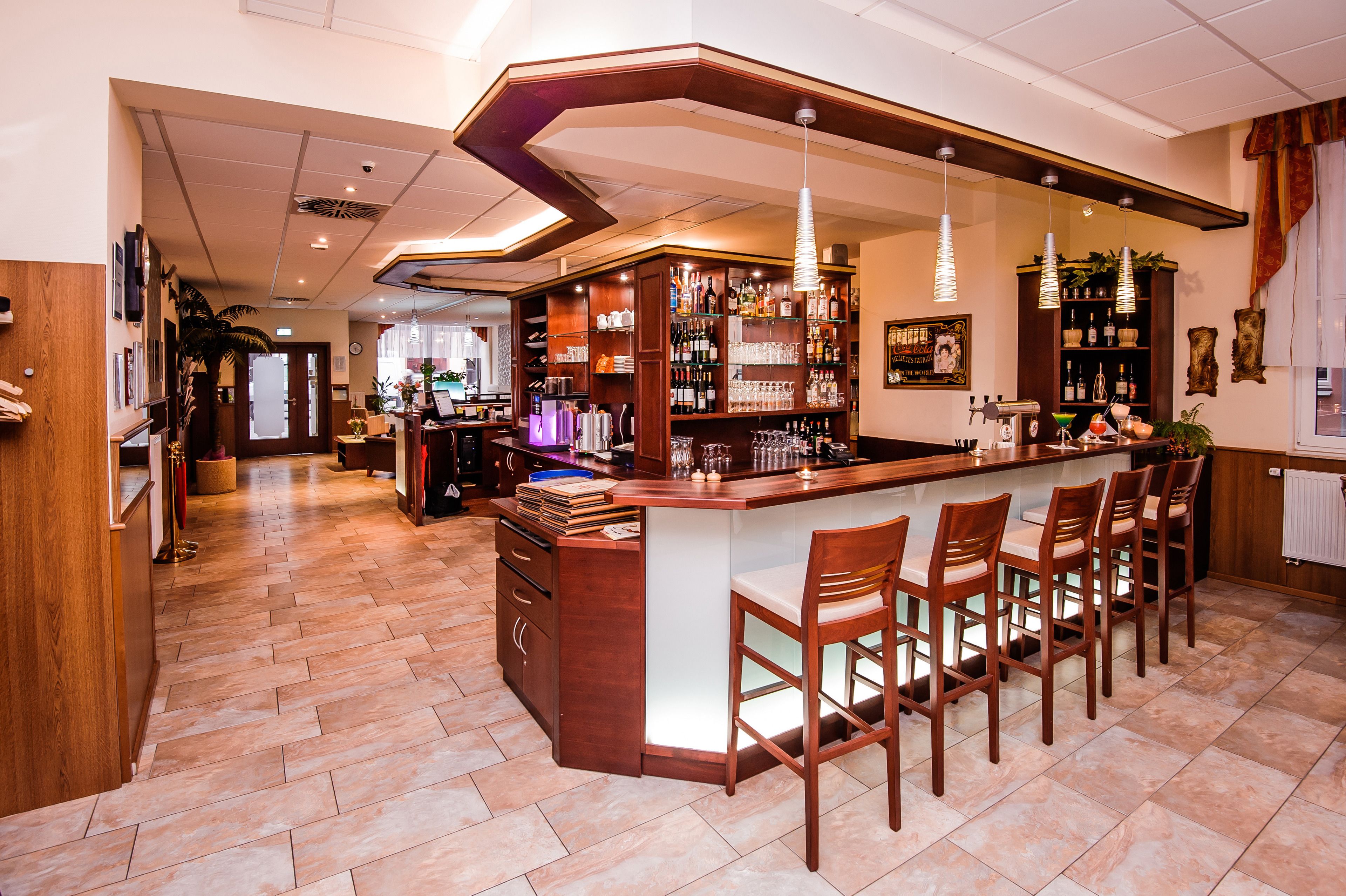A bar area with a curved counter, multiple bar stools, and a variety of bottles and glasses on shelves.