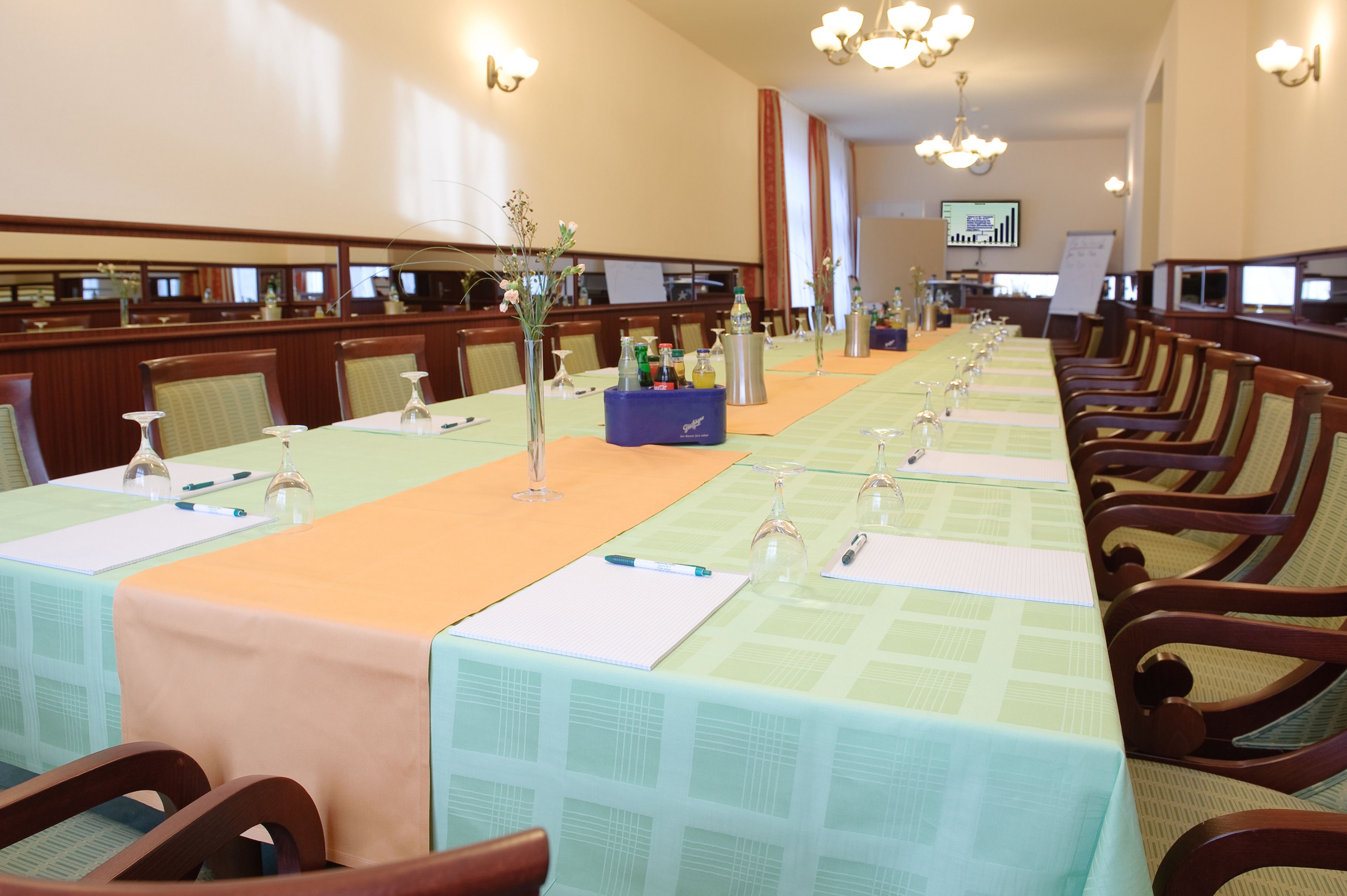 Ett konferensrum med långa bord, stolar och en projektorduk.