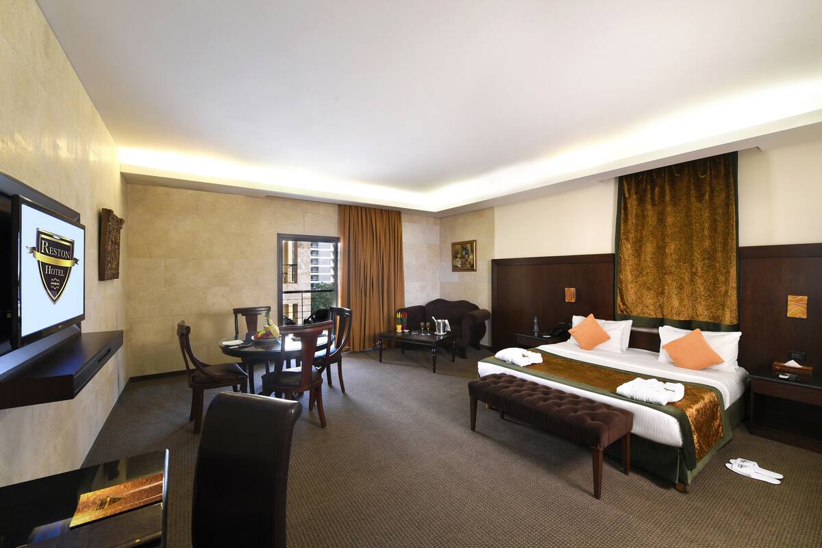Une chambre d’hôtel avec un lit, un bureau, une chaise, une télévision et une fenêtre.