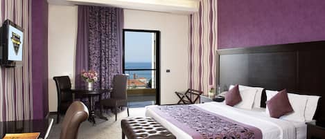 Habitación de hotel con cama, escritorio, silla y vista al mar.