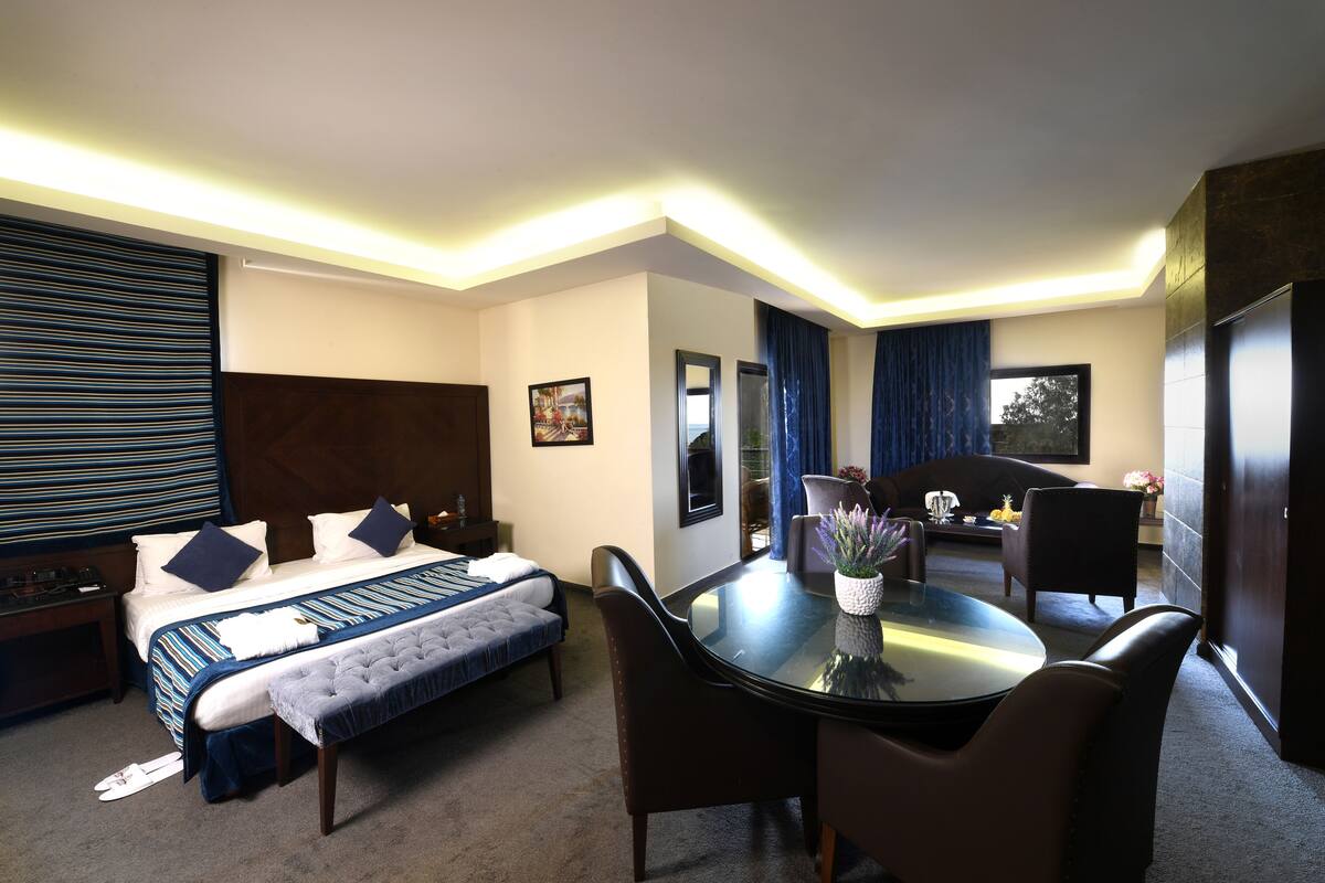 Une chambre d’hôtel avec un lit, un bureau, une chaise, une table ronde et une fenêtre.