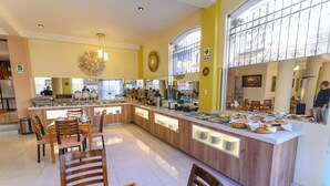 A spacious kitchen area with a central island, wooden chairs, and a buffet setup. - Sol Plaza Hotel (Puno)