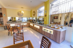 A spacious kitchen area with a central island, wooden chairs, and a buffet setup.