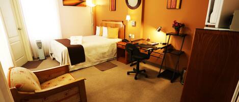 Una habitación de hotel con cama, escritorio, silla y un pequeño sofá.