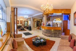 A hotel lobby with a reception desk, seating area, chandelier, and artwork.
