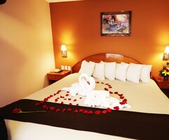 Una habitación de hotel con una cama bien hecha, un cuadro en la pared y una mesita de noche con una lámpara y un teléfono.