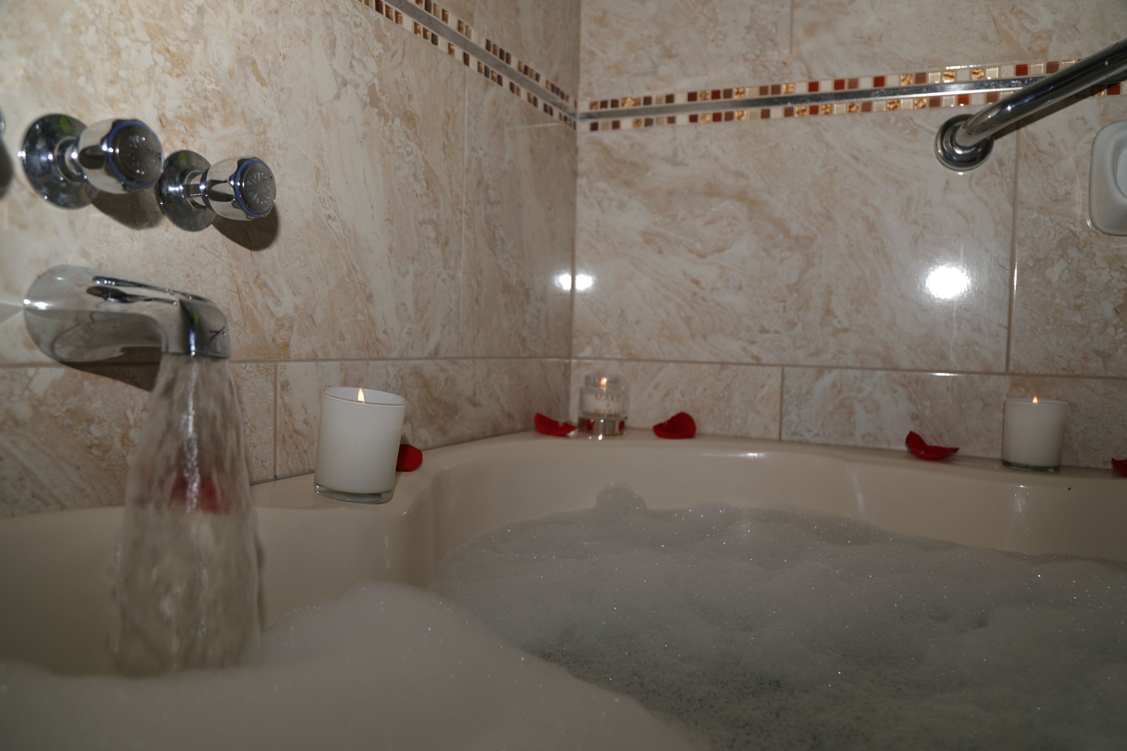A bathroom with a bathtub, a showerhead, and a wall-mounted faucet.