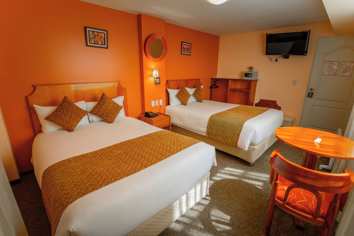Habitación de hotel con dos camas, un televisor, un escritorio y una silla.