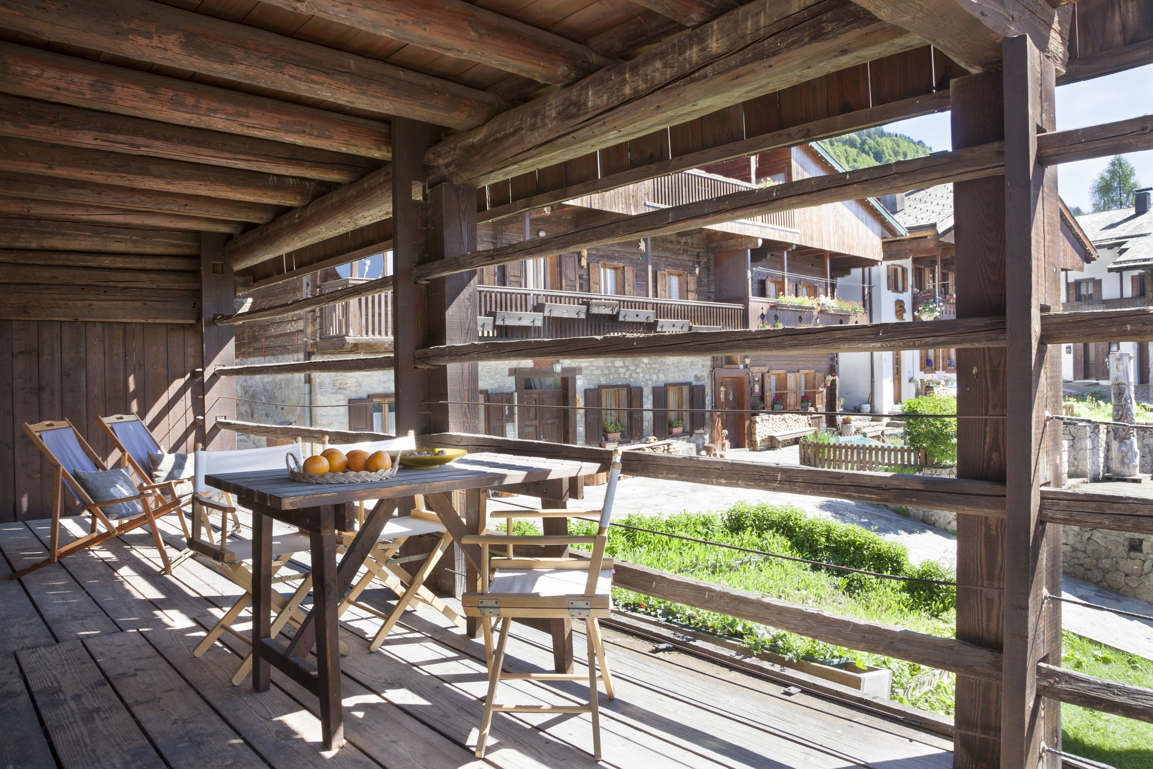 Une terrasse en bois avec une table et des chaises, offrant une vue pittoresque sur un village.