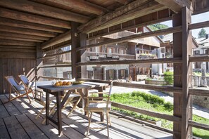 A wooden deck with a table and chairs, overlooking a scenic village. - Albergo Diffuso Sauris In Sauris di Sopra (Sauris)