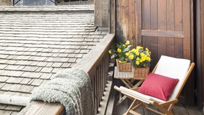 A wooden balcony with a wooden chair and a table with flowers. - Albergo Diffuso Sauris In Sauris di Sopra (Sauris)