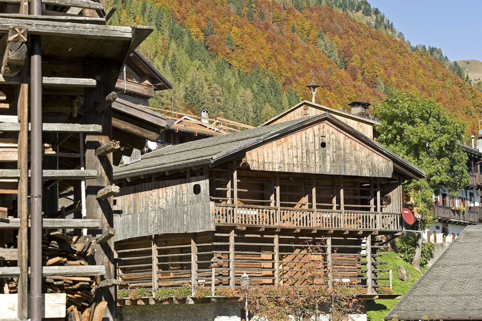 A wooden building with a balcony, surrounded by a mountainous landscape.