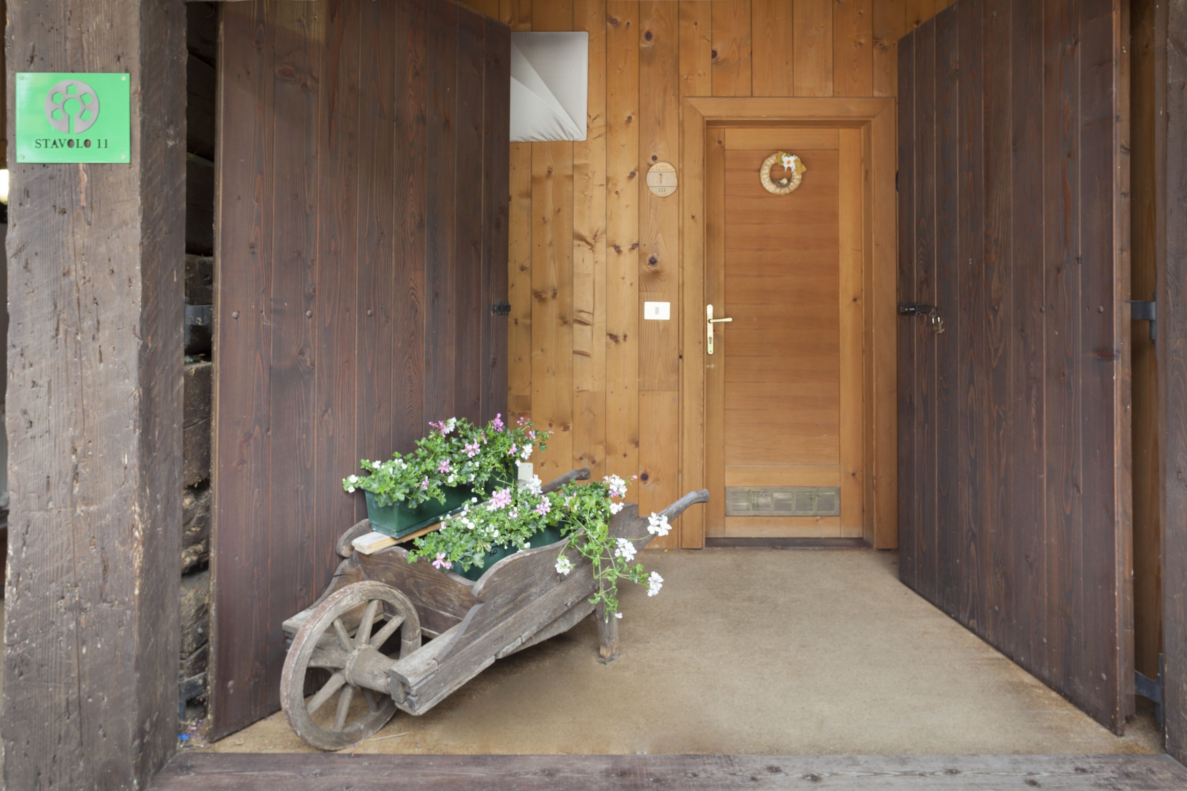 Una puerta de madera con un pequeño arreglo floral y una señal encima.