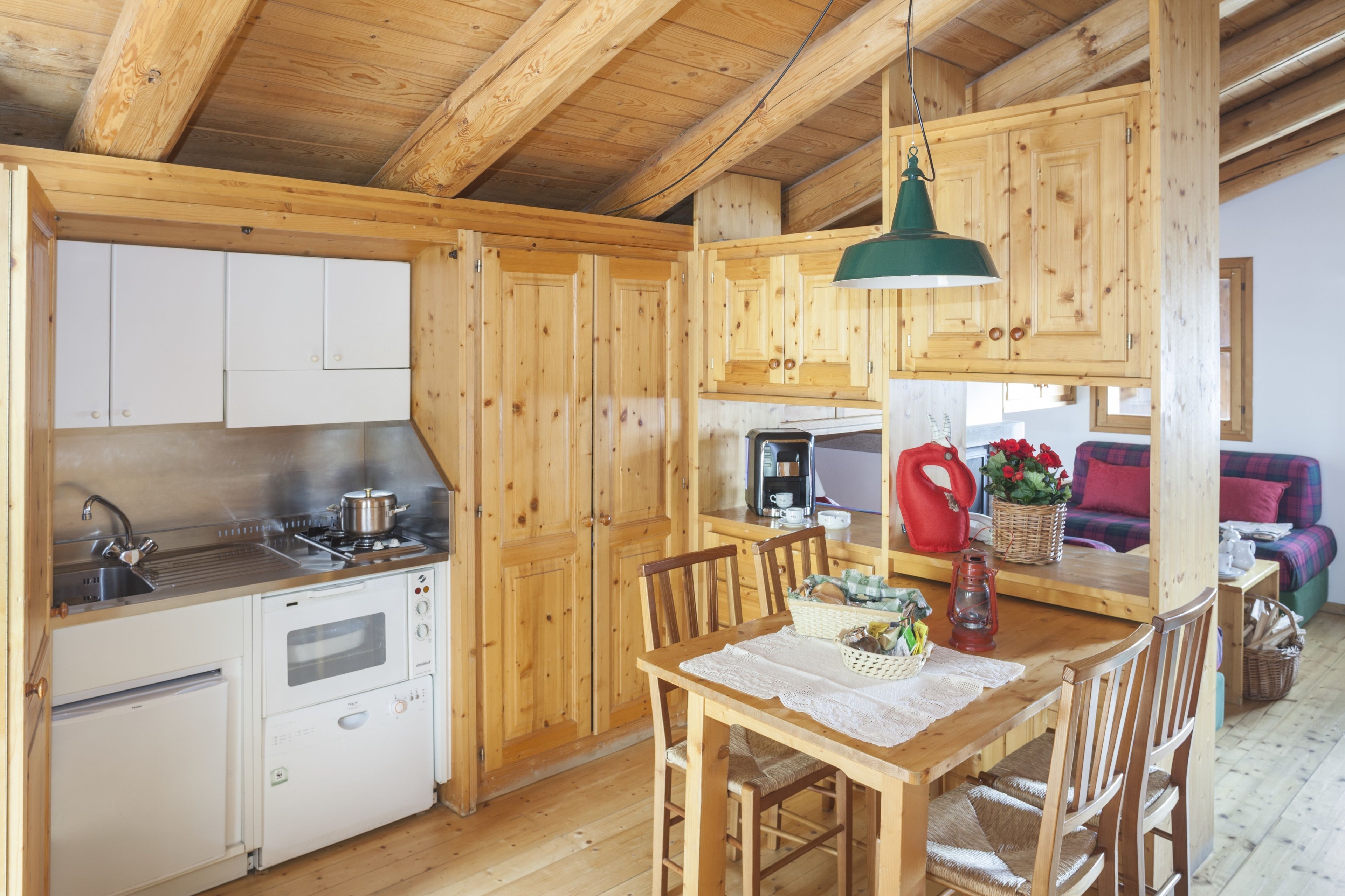 Una cocina compacta con armarios de madera, horno empotrado y comedor con mesa y sillas.