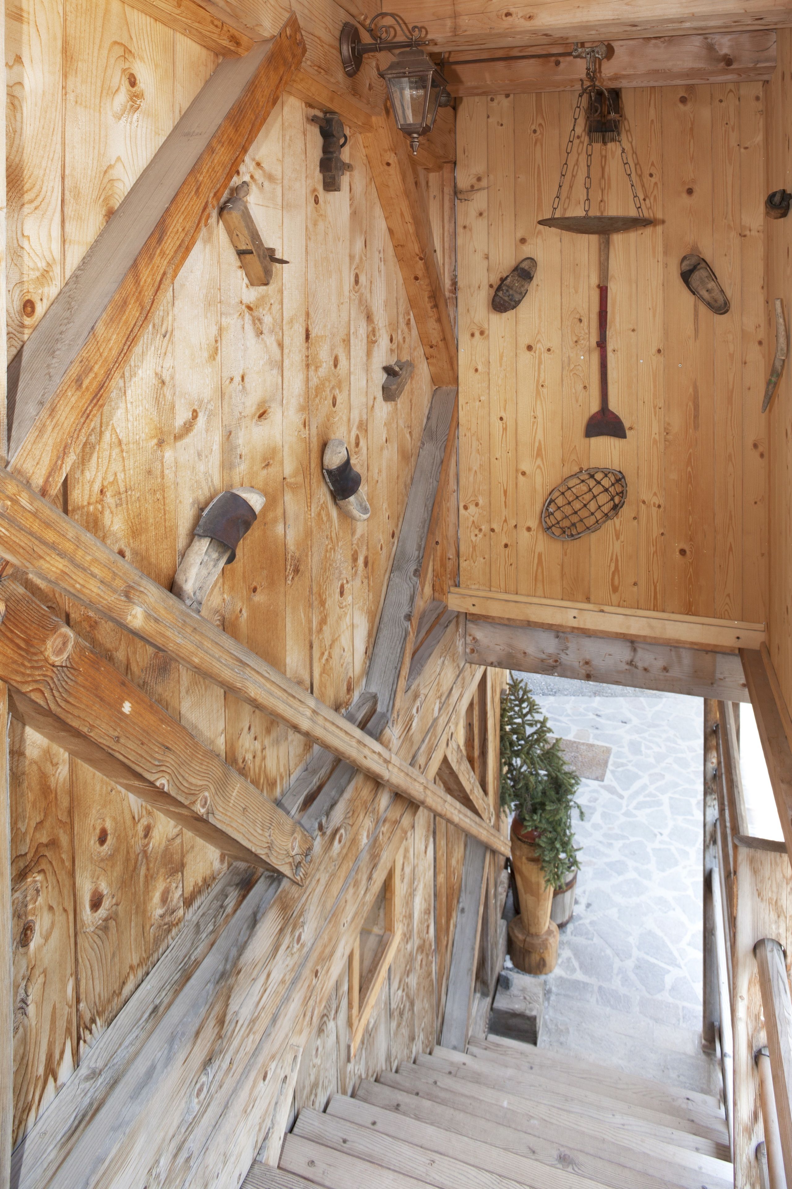 A wooden staircase with a stone floor, wooden railings, and a hanging lantern.