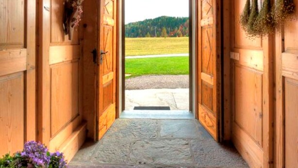 A wooden hallway leading to a door with a view of a green field. - Albergo Diffuso Sauris In Sauris di Sopra (Sauris)