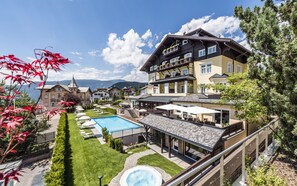 Et hotel med swimmingpool, udendørs siddepladser og udsigt til bjerge.