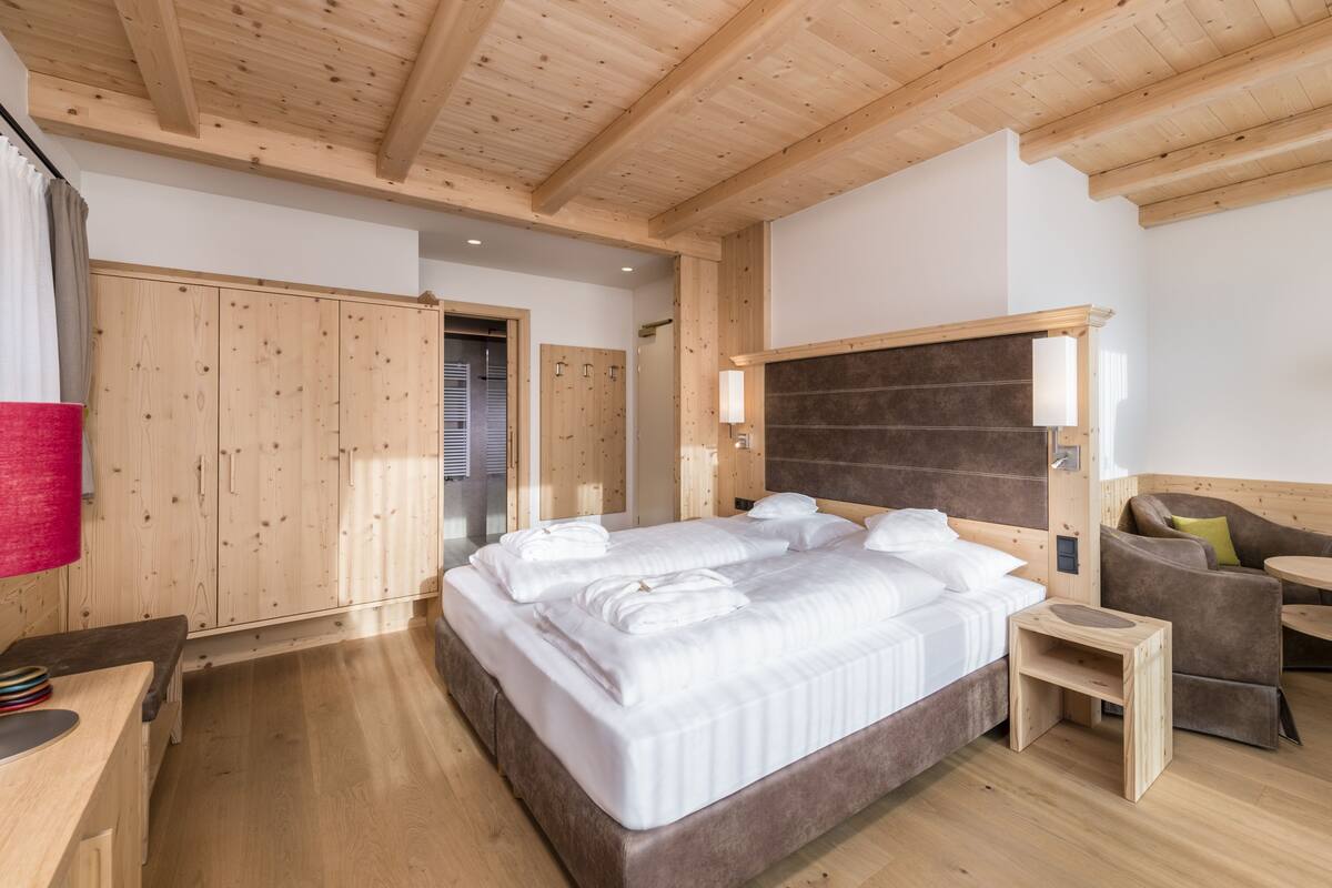 A wooden-paneled bedroom with a bed, a small table, and a sofa.