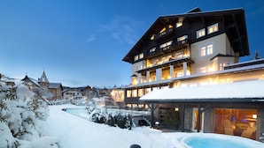 A multi-story hotel with a snow-covered exterior and a hot tub area. - Hotel Villa Kastelruth (Castelrotto)