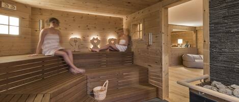A sauna with wooden benches and a stone wall.