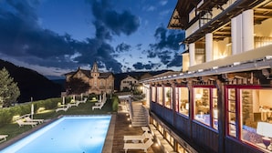 A pool area with lounge chairs and a staircase leading to a building with large windows. - Hotel Villa Kastelruth (Castelrotto)